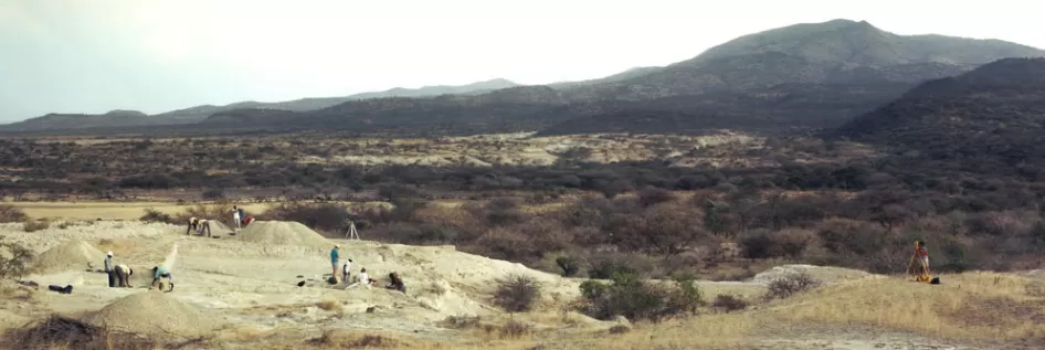 肯尼亚考古遗址Olorgesailie的全景，九个人在挖掘和看着山
