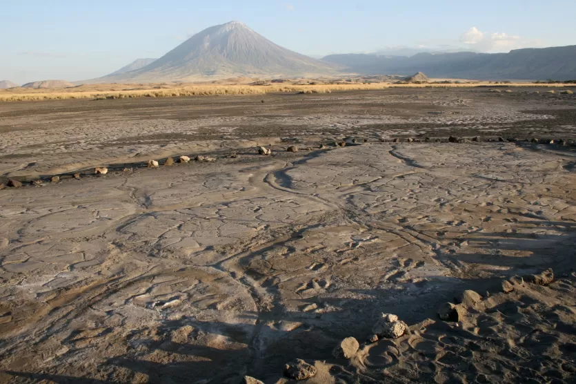 400年一个古老的人类足迹的火山泥流在前台,至今仍火山,Oldoinyo L 'engai,在遥远的背景