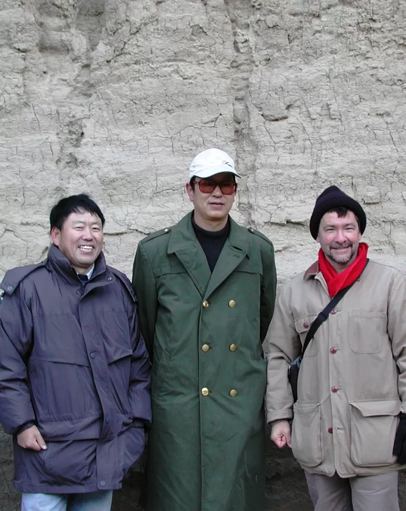 朱博士Rixiang,范教授谢和里克•波茨博士在温暖的大衣和帽子站在面前的分层,基坑的灰色的墙