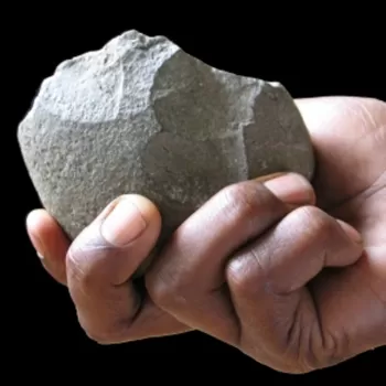现代人类的手拿着一块石头工具。